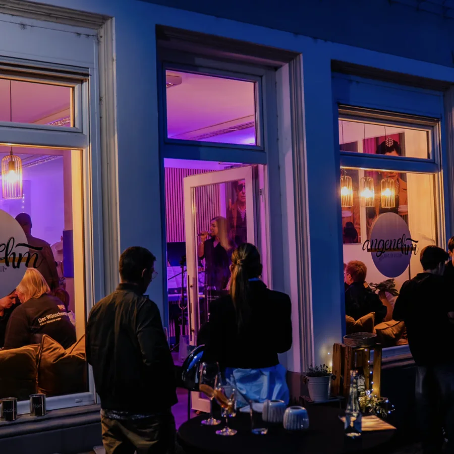 Abends vor dem Angenehm: Publikum vor der geöffneten Fensterfront, drinnen singt jemand