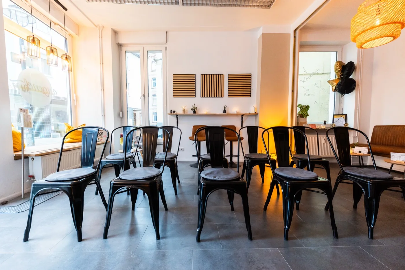Der Gastraum im Angenehm: helle Wände, lange Tafel, Stühle und warmes Licht